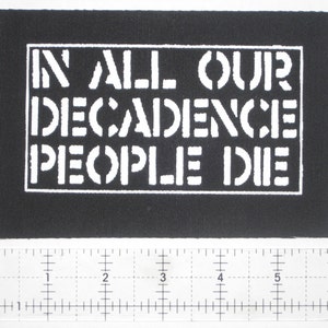 Peut inclure: Patch noir et blanc avec le texte "IN ALL OUR DECADENCE PEOPLE DIE" dans un rectangle blanc.
