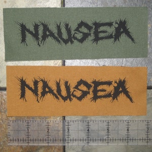 May include: Two fabric patches with the word "NAUSEA" printed in black on them. The top patch is green and the bottom patch is orange.