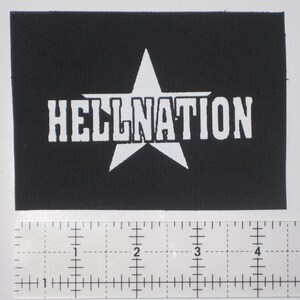 Könnte beinhalten: Schwarzer Stoff-Patch mit einem weißen Stern und dem Text "HELLNATION" in weiß.