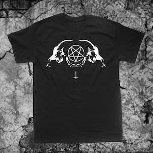 Könnte beinhalten: Schwarzes T-Shirt mit einem weißen Aufdruck von zwei Ziegenköpfen, die sich gegenüberstehen, mit einem Pentagramm dazwischen. Unter den Schädeln befindet sich ein weißes umgekehrtes Kreuz.