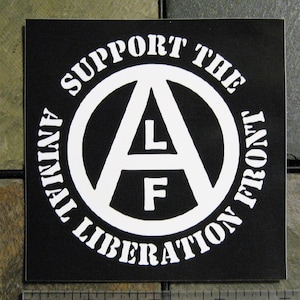May include: Black and white sticker with the text "Support the Animal Liberation Front" in a circle around a white anarchy symbol with the letters "L" and "F" inside.