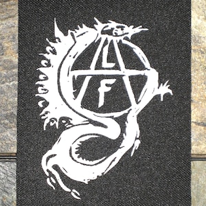 Puede incluir: Parche bordado en blanco y negro con un dragón envuelto alrededor de un símbolo de anarquía con la letra "F" en su interior. El parche mide aproximadamente 7,6 cm de ancho.