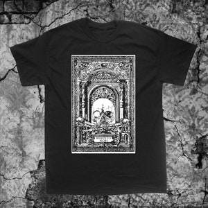 以下が含まれることがあります： 黒いTシャツに、白い骨格のグラフィックプリントが施されています。骨格は装飾的なフレームの中にあり、その下に「MEMENTO MORI」という文字が印刷されています。