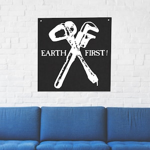May include: Black and white graphic print of a wrench and a hammer crossed over each other. The text "EARTH FIRST!" is printed below the tools.