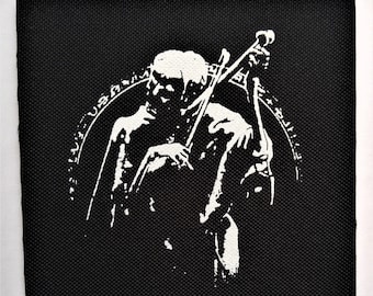 Könnte beinhalten: Schwarz-weiß-Patch mit einer skelettartigen Figur, die Cello spielt. Die Figur ist von einem Kreis mit Text umgeben.
