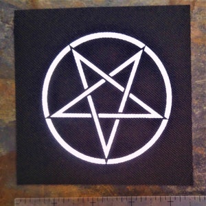 Könnte beinhalten: Ein weißes Pentagramm, oder fünfzackiger Stern, ist in einem weißen Kreis auf einem schwarzen Stoffstück zentriert.