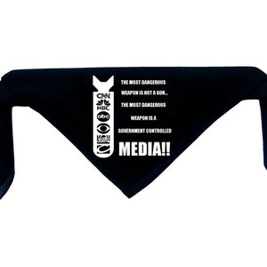 Może przedstawiać: Czarna bandana z białym nadrukiem bomby i tekstem "THE MOST DANGEROUS WEAPON IS NOT A GUN... THE MOST DANGEROUS WEAPON IS A GOVERNMENT CONTROLLED MEDIA!!" z logo CNN, NBC, ABC, FOX i CBS.
