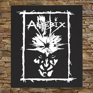 May include: Black and white patch with a stylized image of a face with a spiky crown and the word "Amebix" in a bold, stylized font.