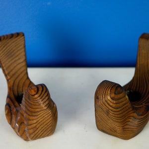 May include: Two wooden wall hooks shaped like hands, with a brown wood grain finish.