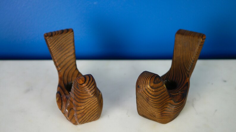 May include: Two wooden wall hooks shaped like hands, with a brown wood grain finish.