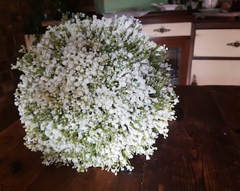 May include: A white bridal bouquet made of baby's breath flowers. The bouquet is round and full, with a delicate and airy look.