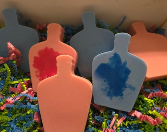 May include: Five decorative soap bars shaped like bottles, in a box filled with colorful crinkle paper. The soaps are in shades of blue and pink, with some having a painted design.