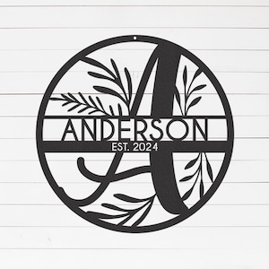 Peut inclure: Cercle en métal noir avec une lettre A stylisée et le texte "ANDERSON EST. 2024" à l'intérieur. La lettre A est entourée de motifs floraux.