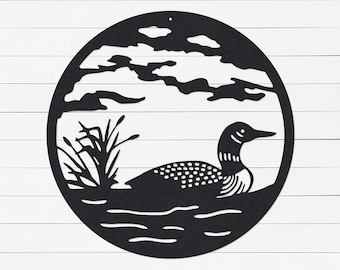 May include: Black metal wall art depicting a loon swimming in a lake with reeds and clouds in the background. The art is circular in shape.