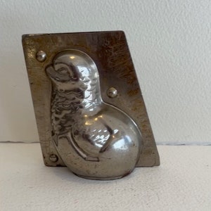 May include: A vintage metal mould for making chocolate shaped like a bird. The mould is silver in colour and has a detailed design.