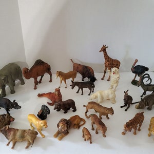 May include: A collection of 20 plastic animal figurines, including a giraffe, elephant, camel, lion, tiger, zebra, bear, rhino, ostrich, and more. The figurines are all in various poses and are made of a realistic-looking plastic.