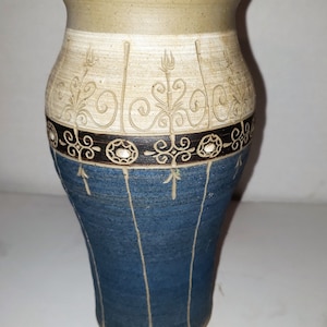 May include: A blue and white ceramic vase with a decorative design. The vase has a wide mouth and a narrow base.