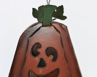 Könnte beinhalten: Ein hölzerner Kürbis mit einem geschnitzten Jack-o'-Lantern-Gesicht. Der Kürbis ist in Braun- und Orangetönen bemalt und hat einen grünen Stiel. Er hat eine Drahtschlaufe zum Aufhängen.