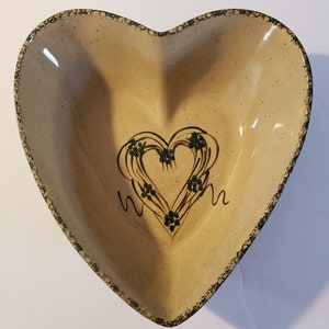 May include: A heart-shaped ceramic bowl with a brown glaze and a green painted heart design. The heart has a leafy design and the words "Mom" on either side.
