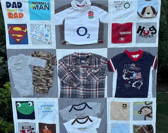 May include: A handmade quilt featuring squares of various children's clothing items. The quilt includes shirts and onesies with text and graphics, such as "DAD thinks I'm RAD", a Superman logo, and a shirt with the text "US". The quilt is a mix of colors.