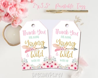 Op de afbeelding: Twee rechthoekige witte papieren labels van 5,08 cm bij 8,89 cm, met de roze en groenblauwe tekst Thank You For Being Young & Wild With Me, een gouden glitterpijl en roze bloemillustraties aan de onderkant van elk label.