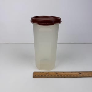 May include: A white ceramic mug with a black handle and the text "But First, Coffee" in a bold, black font. The mug is sitting on a wooden surface. The mug is approximately 4 inches tall.