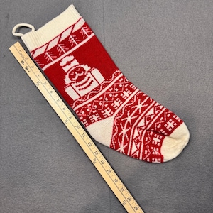 Puede incluir: Calcetín navideño de punto rojo y blanco con un diseño de Papá Noel. El calcetín tiene un lazo para colgar y mide aproximadamente 48 cm de largo.