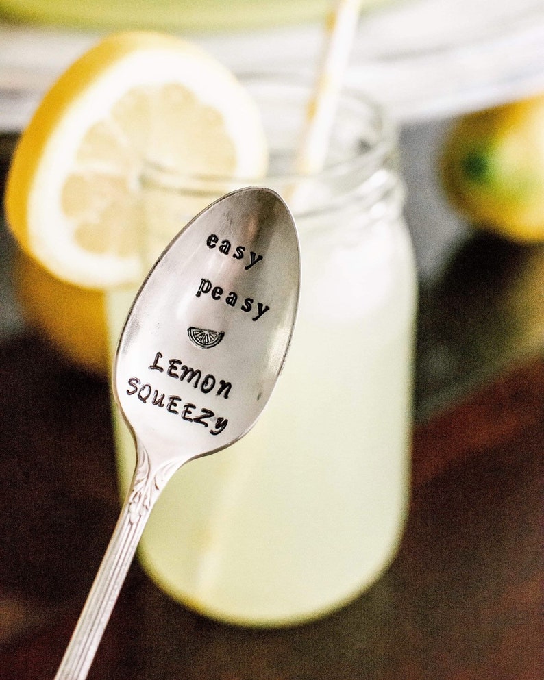 Puede incluir: Una cuchara de plata con las palabras "easy peasy lemon squeezy" grabadas en ella. La cuchara est&aacute; delante de un vaso de limonada con una rodaja de lim&oacute;n.