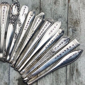 May include: A collection of vintage silverware spoons with various herbs and spices names engraved on them, including oregano, basil, thyme, and rosemary.