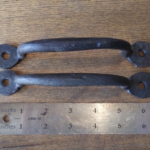 May include: Two black metal door pulls with rounded ends and a hole in the center. The pulls are approximately 4 inches long and are shown next to a ruler.