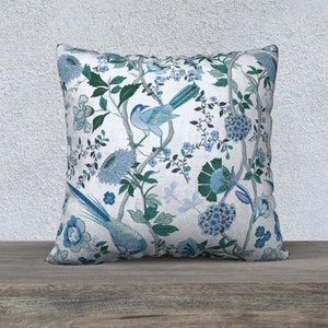 May include: A white cushion with a blue and green floral pattern featuring birds. The cushion is square shaped and has a soft, comfortable feel.