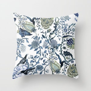 May include: A white throw pillow with a blue and green floral pattern. The pattern features stylised flowers, leaves, and birds.