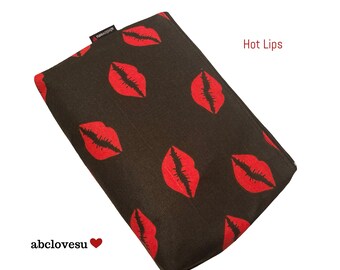 May include: A rectangular, black case with a repeating pattern of red lips. The text "Hot Lips" is in red on the right side of the case. The brand name "abclovesu" is on the bottom left.