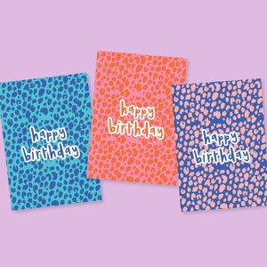 Puede incluir: Tres tarjetas de felicitación con un patrón de estampado de leopardo en azul, rosa y naranja. Cada tarjeta dice "feliz cumpleaños" en texto blanco.