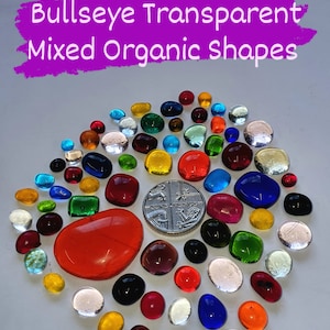 May include: A collection of colourful, transparent, organic-shaped glass pieces in various sizes and colours, including red, orange, yellow, green, blue, and purple. A silver coin is also included in the image.