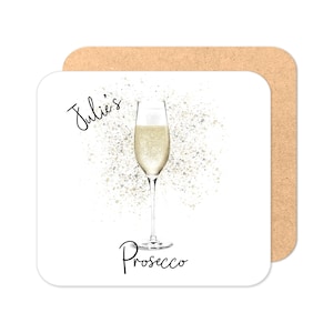 May include: A white coaster with a gold glitter background and a glass of prosecco. The text "Julie's Prosecco" is written in black.