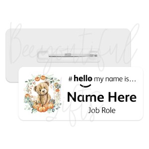 May include: White name tag with a cute cartoon bear holding pumpkins. The tag says "#hello my name is... Name Here Job Role".