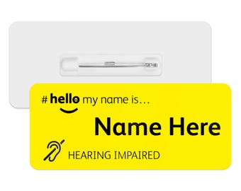 May include: Yellow name tag with a black hashtag, smiley face, and the text "#hello my name is... Name Here HEARING IMPAIRED". The tag has a pin on the back.