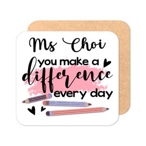 May include: A white square coaster with the text "Ms. Choi you make a difference every day" in black cursive font. A pink watercolor-style background with three colored pencils is behind the text. Two small hearts are below the pencils.