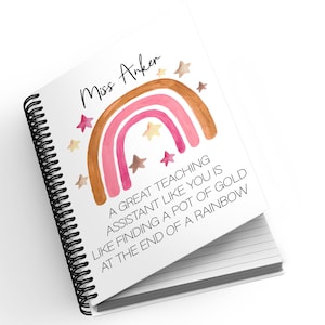 May include: A spiral bound notebook with a white cover featuring a watercolour rainbow with stars and the text "Miss Anker A GREAT TEACHING ASSISTANT LIKE YOU IS LIKE FINDING A POT OF GOLD AT THE END OF A RAINBOW".
