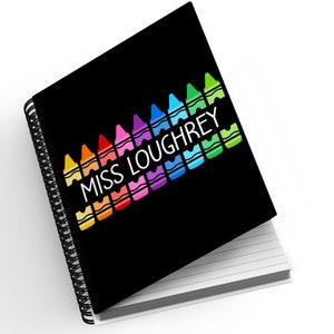 May include: Black spiral notebook with a rainbow of crayons and the text "Miss Loughrey" on the cover.