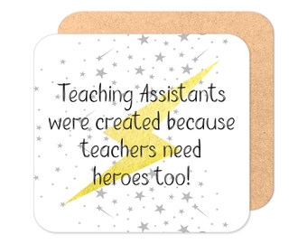 May include: A white coaster with a yellow lightning bolt and silver stars. The text on the coaster reads "Teaching Assistants were created because teachers need heroes too!"