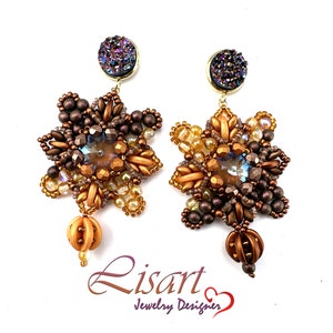 Puede incluir: Un par de pendientes de cuentas doradas y marrones con una piedra púrpura e iridiscente en la parte superior. Los pendientes tienen forma de estrella y tienen una cuenta colgante en la parte inferior. Los pendientes están etiquetados como "Lisart Jewelry Designer".