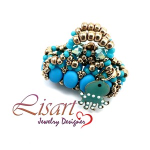 Può includere: Un anello di perline turchesi e dorate con un ciondolo a forma di polpo turchese. L'anello è realizzato con perline piccole e ha un design unico.