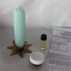 May include: A green candle, white candle, oil bottle, incense, and a spell kit for prosperity and luck. The kit includes instructions for a spell to bring prosperity and luck. The instructions include the text "POWER WITHIN PROSPERITY SPELL KIT PROSPERITY AND LUCK".