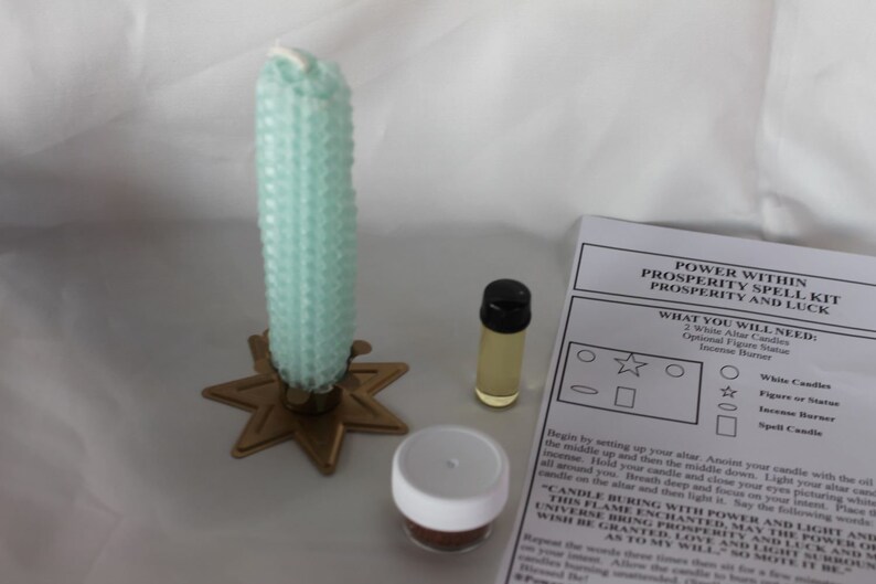 May include: A green candle, white candle, oil bottle, incense, and a spell kit for prosperity and luck. The kit includes instructions for a spell to bring prosperity and luck. The instructions include the text "POWER WITHIN PROSPERITY SPELL KIT PROSPERITY AND LUCK".
