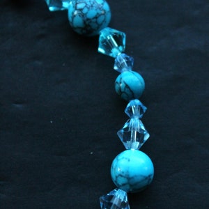 May include: A turquoise and clear blue beaded necklace with alternating round and faceted beads.