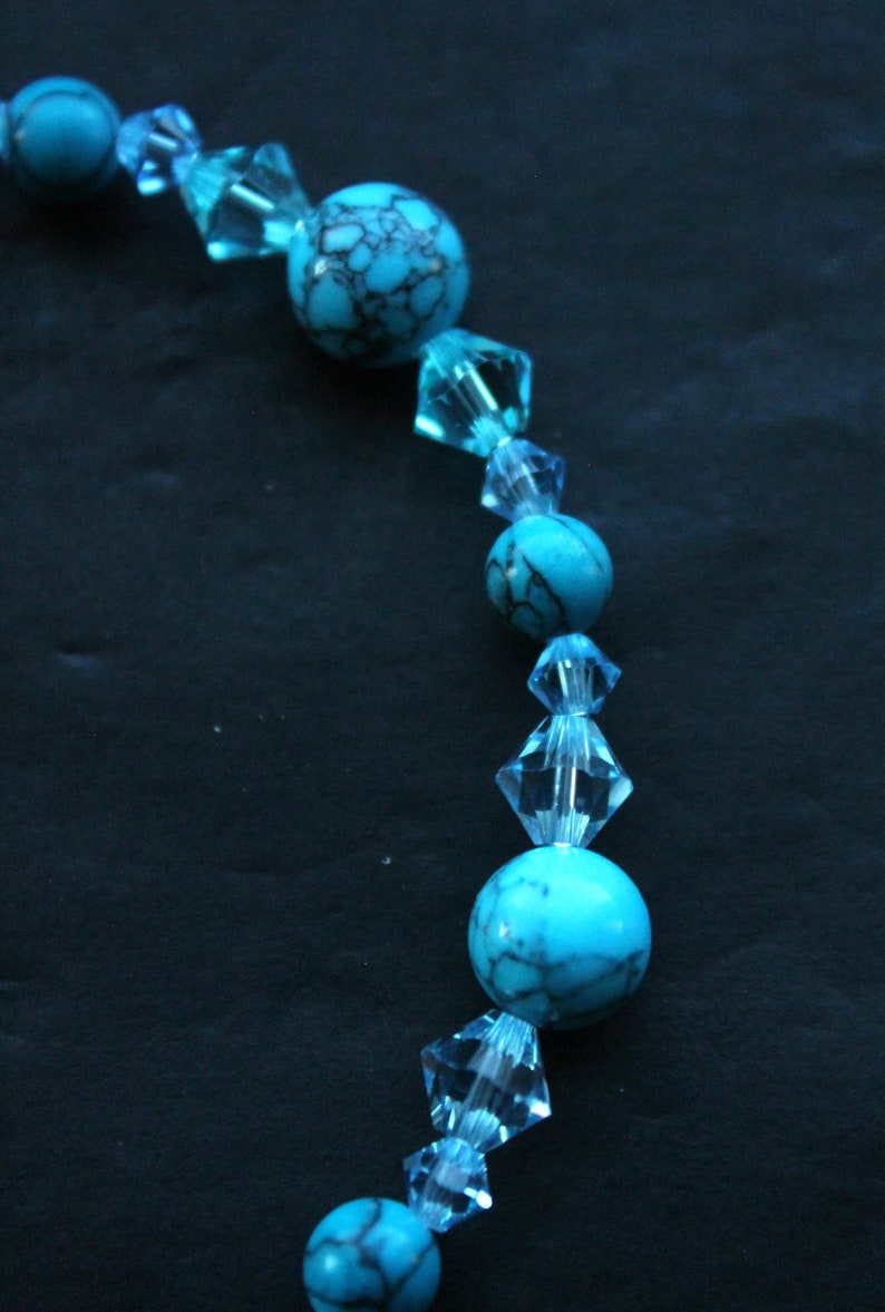 May include: A turquoise and clear blue beaded necklace with alternating round and faceted beads.