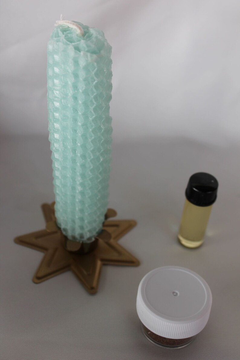May include: A teal honeycomb candle on a gold star-shaped candle holder, a small clear bottle with a black lid containing oil, and a small white jar with a brown substance inside.