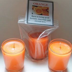 May include: Three orange-colored votive candles in clear glass holders. One candle is in a plastic bag with a label that reads "ORANGE" and "Burn to bring good fortune, marriage and eternal love."